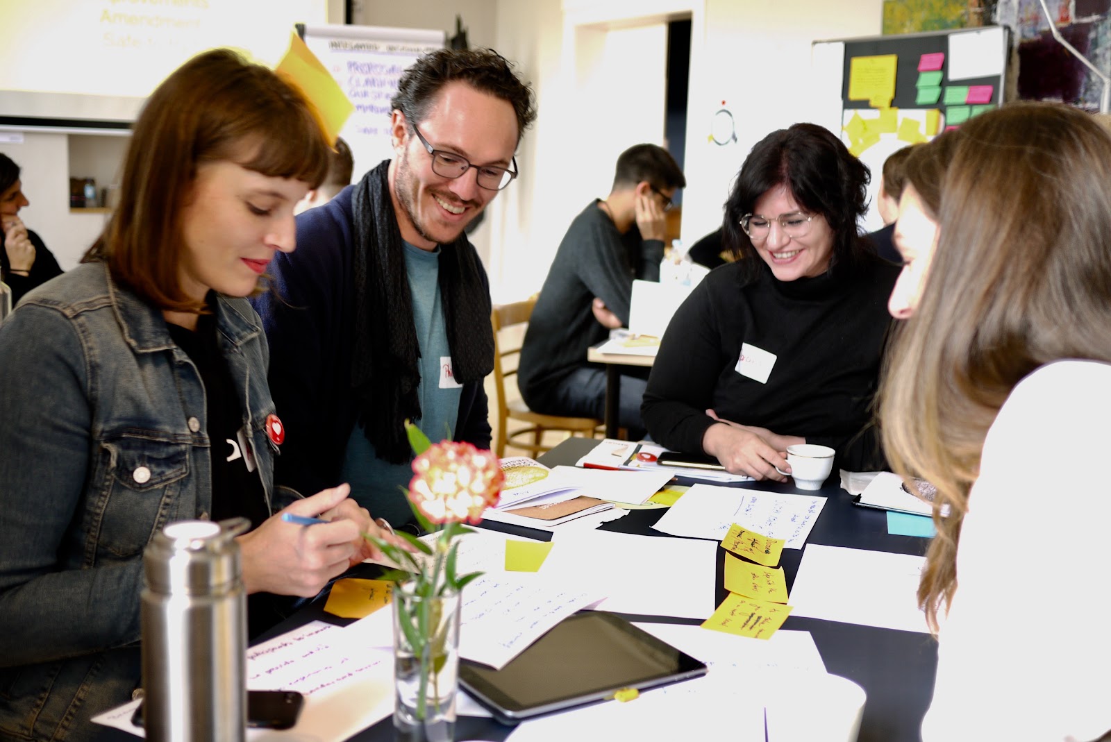 A team around a table covered in sticky notes, prototyping a customer experience during a Kaospilot in-company training